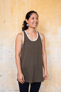 woman is standing with arms to her side while wearing Green Keyhole Tank in front of stained yellowing wall